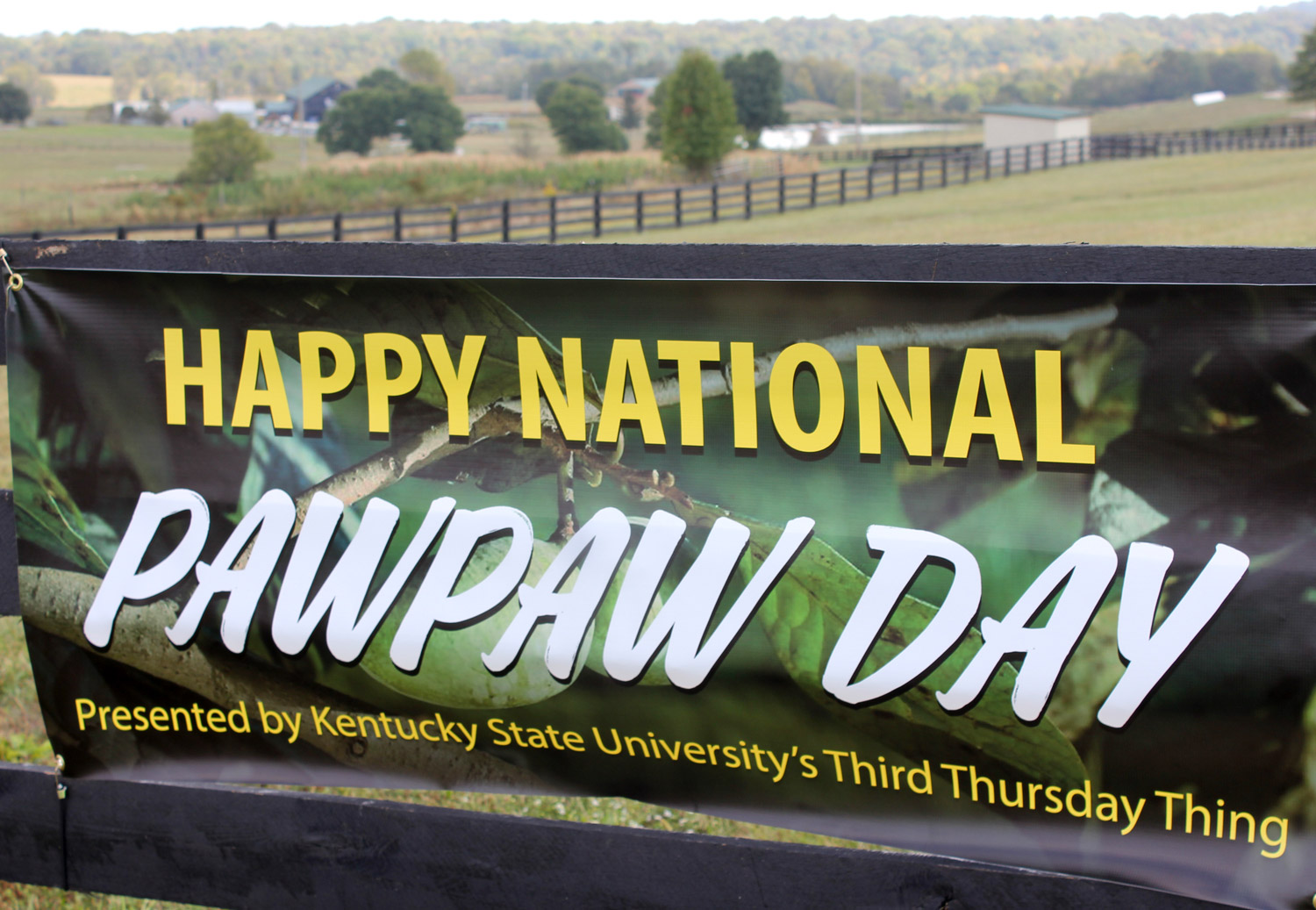 Banner on horse fence proclaiming National Pawpaw Day at KY State University in Frankfort