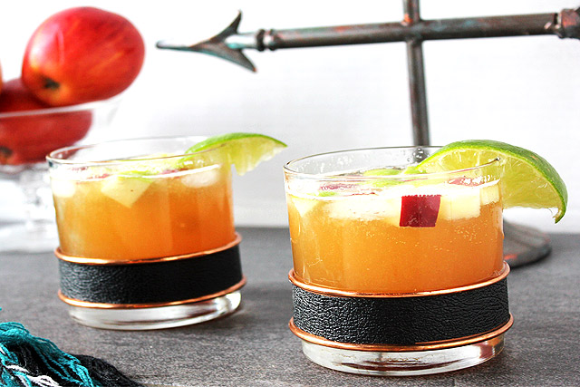 Two Bourbon Apple Cider Cocktails in vintage rocks glasses with bowl of apples in background