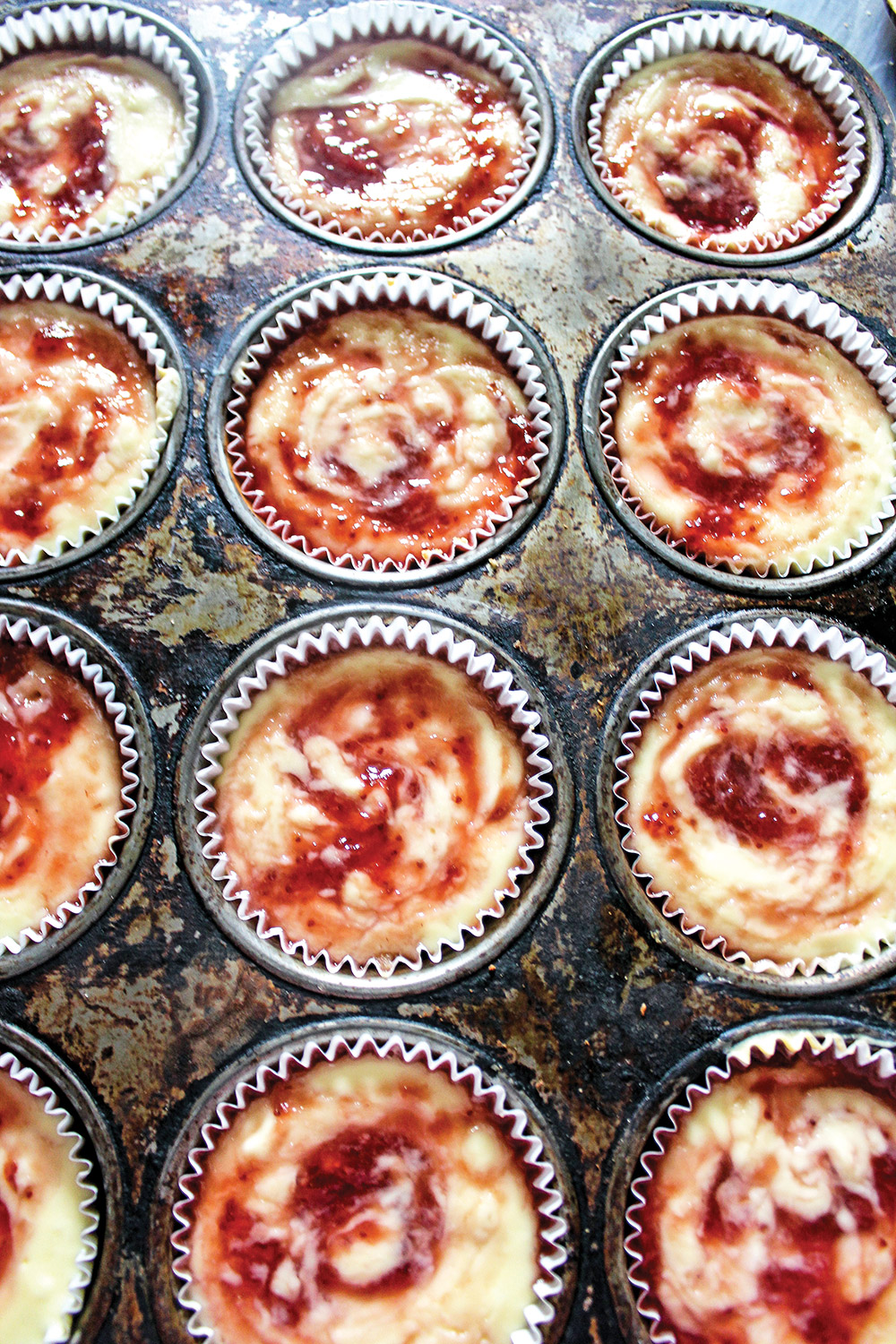 Photo of strawberry jam swirled cheesecakes in vintage muffin tin