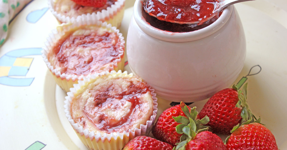 Individual strawberry cheesecake swirls with fresh strawberries and a jam pot of strawberry jam