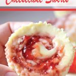 Close-up of hand holding individual cheesecake with strawberry jam swirls
