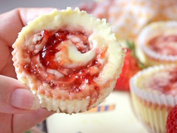 Strawberry Jam Cheesecake Swirls platter with hand holding strawberry dessert