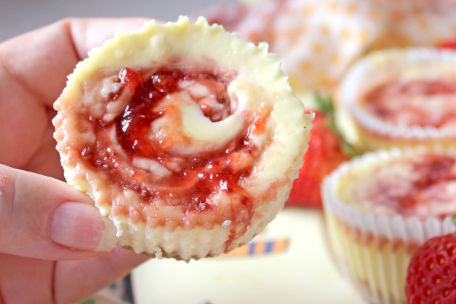 Strawberry Jam Cheesecake Swirls platter with hand holding strawberry dessert