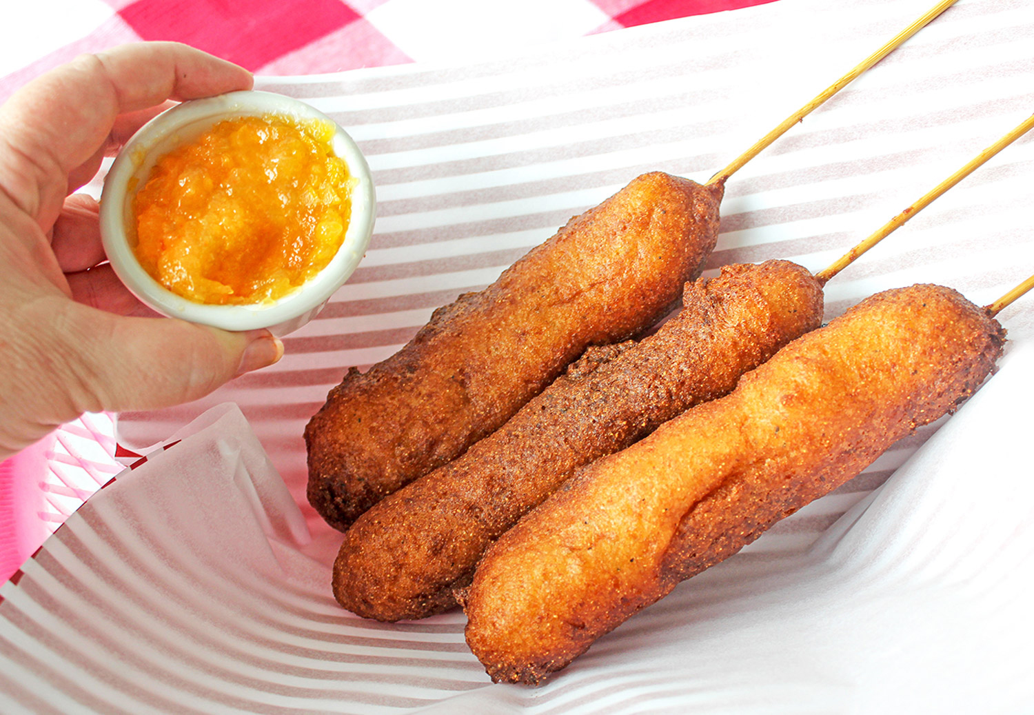 Corn dogs in basket with peach habanero jam dipping bowl