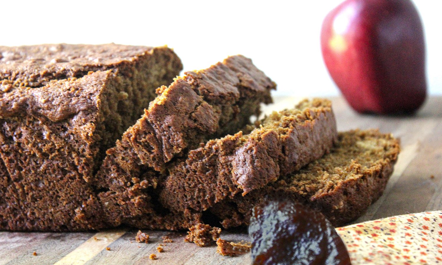 Old fashioned apple bread loaf sliced with fresh shiny red apple in background
