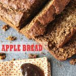 Apple bread loaf placed diagnally on grey slate with a spoon of apple butter resting on yellow calico