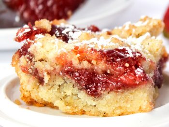 Strawberry jam bar on a white plate with a sprinkle of confectionary sugar