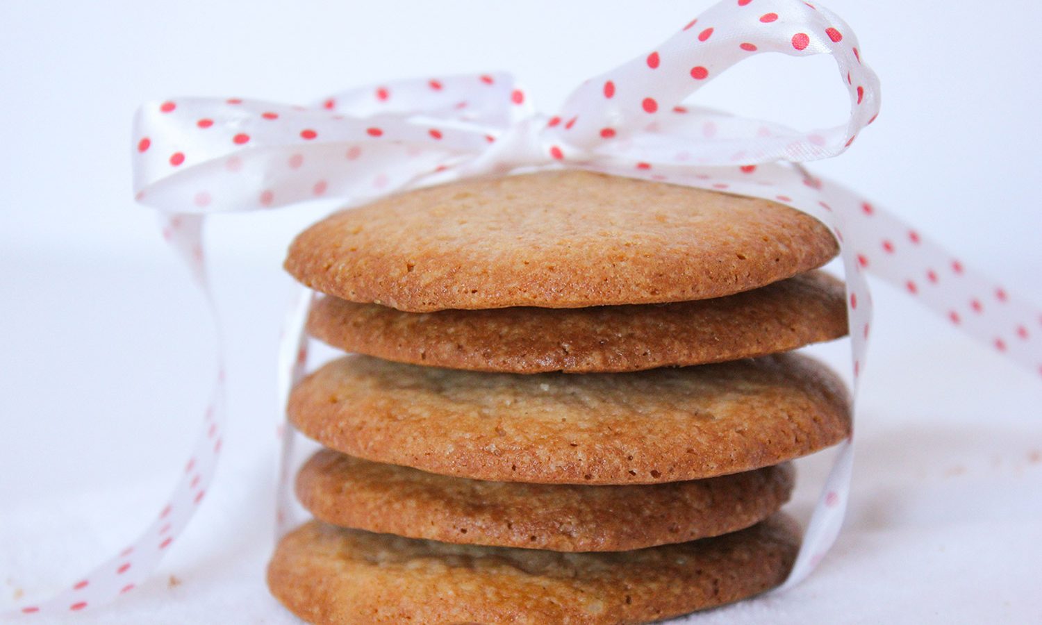 Stack of strawberry jam sugar cookies tied up in a festive red and white polka dot bow