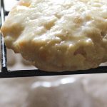 Strawberry shortcake biscuit scones on rack with glaze dripping off.