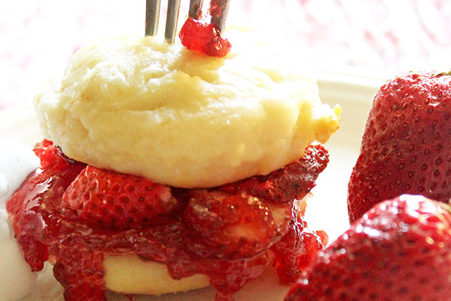 Strawberry shortcake scones layered with strawberry jam and fresh strawberries with a fork sticking straight up in the top