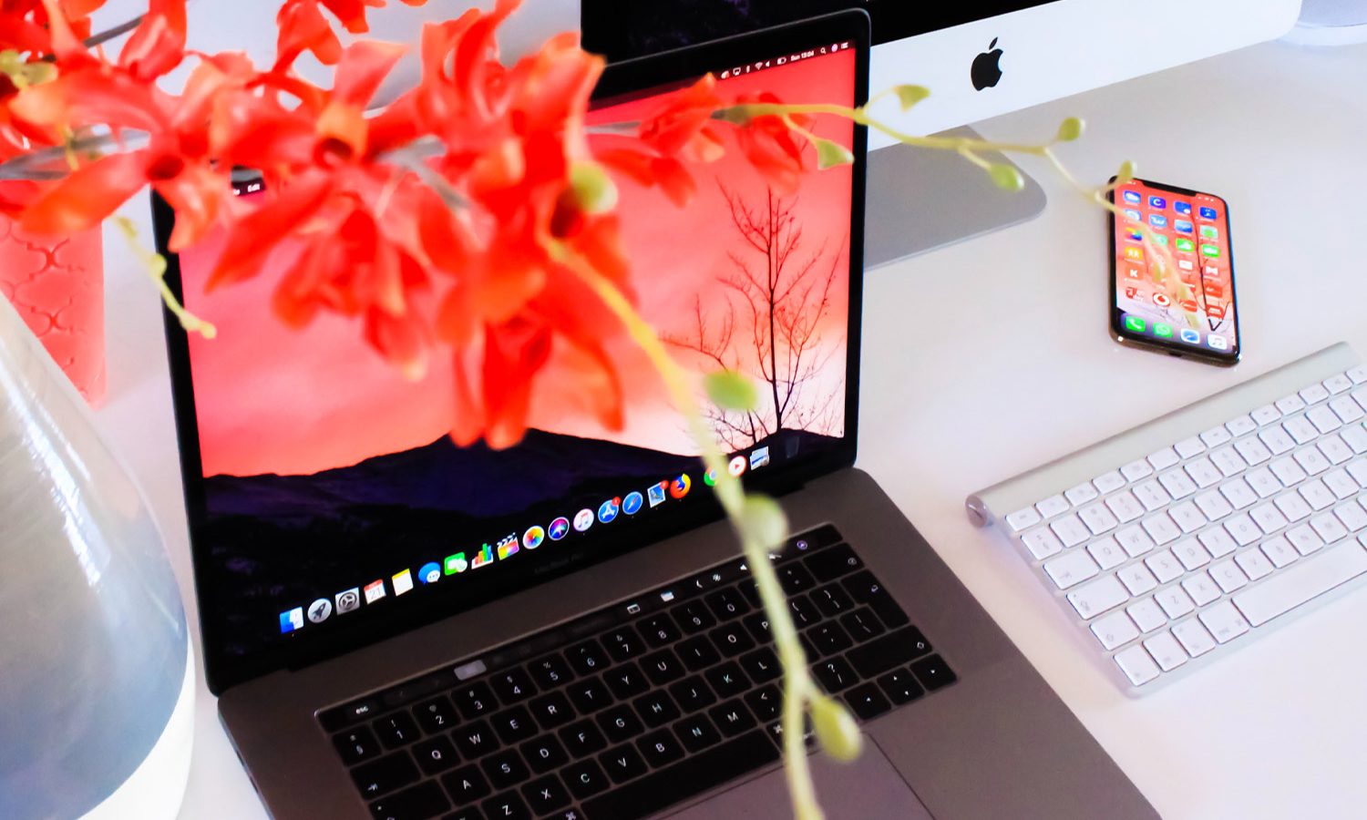 Vase of flowers superimposed over computer keyboarad, iphone, and screen.