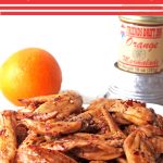 Chicken wings plated for party with fresh orange in background