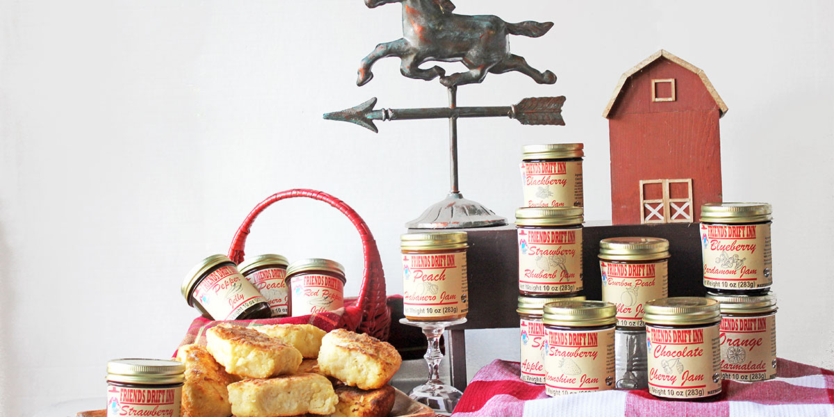Friends Drift Inn jams and jellies with basket of biscuits, horse weather vane, and a wooden barn