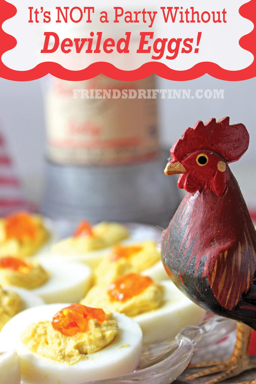 Deviled eggs topped with red pepper jelly and a wooden rooster in foreground