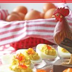 Deviled eggs with pepper jelly, small wooden rooster and basket of eggs.
