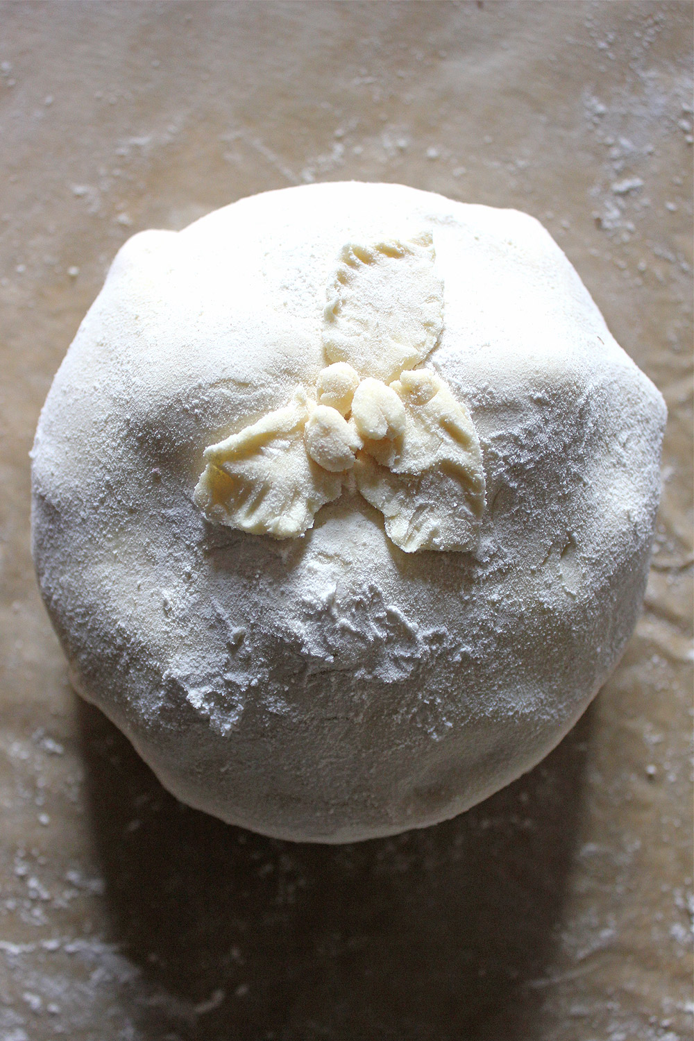 Brie wrapped in uncooked puff pastry with a pastry decoration applied before baking brie.