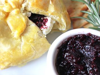 Baked brie berries with jam oozing from puff pastry.