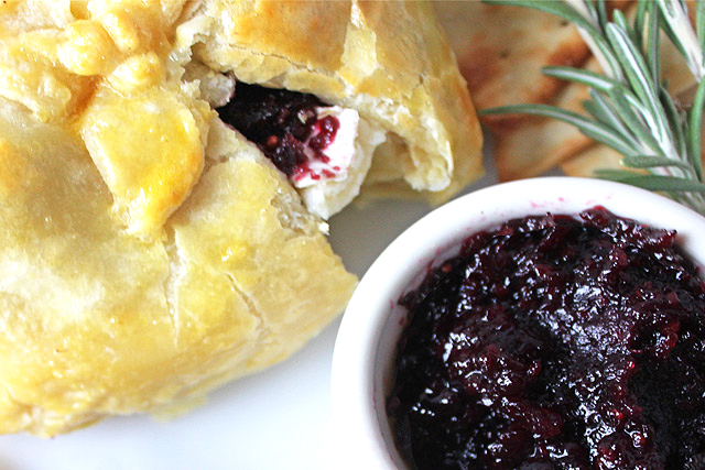 Baked brie berries with jam oozing from puff pastry.