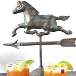 Two bourbon apple cider cocktails with a horse weather vane